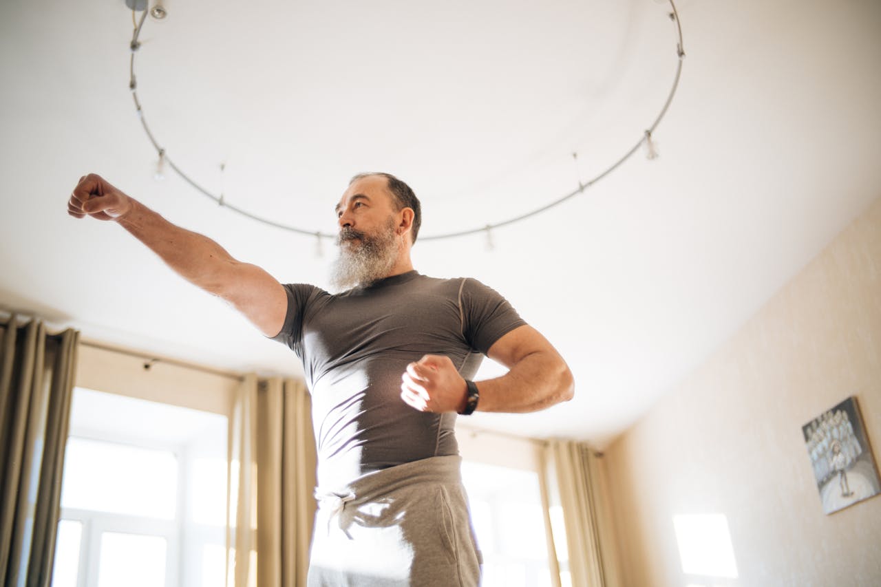 Elderly man performing yoga indoors to stay healthy. Emphasis on active lifestyle and wellness.
